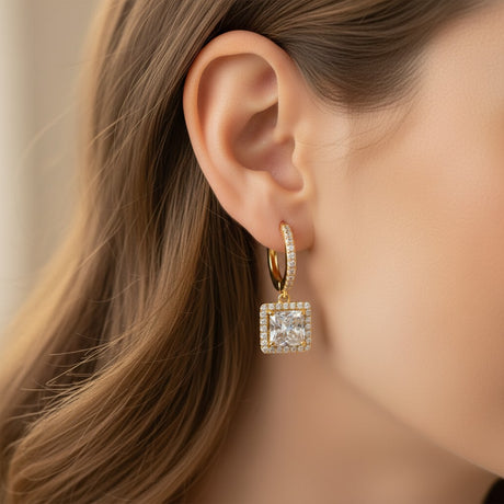 Gold square crystal drop hoop earrings worn by a woman