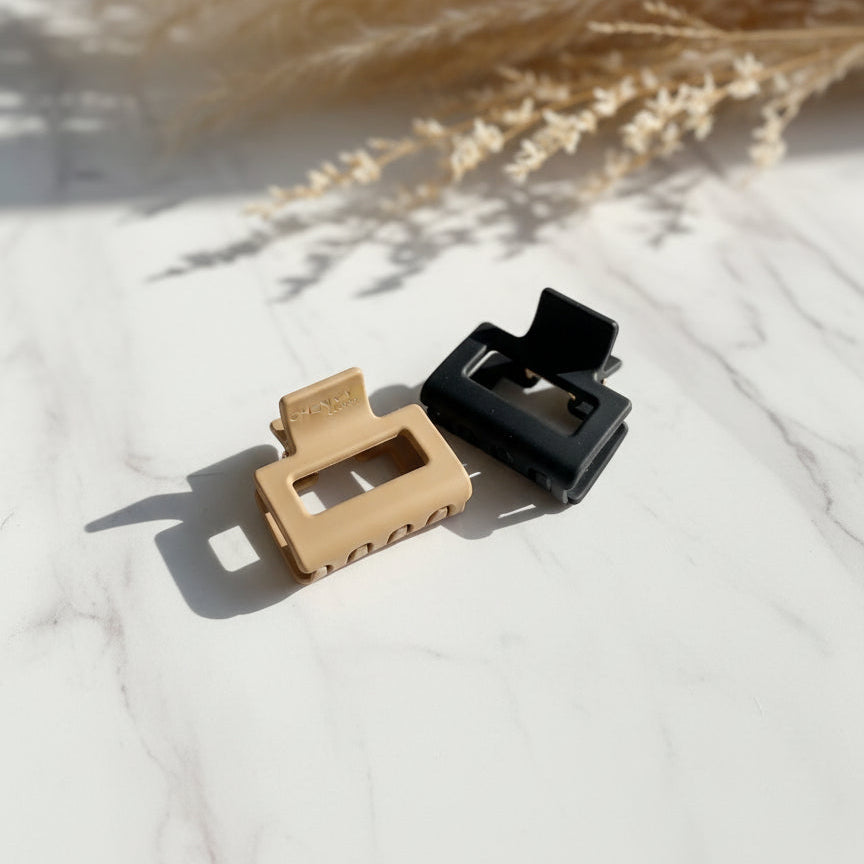 Beige and black square claw clips on white marble with dried pampas grass