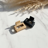 Beige and black square claw clips on white marble with dried pampas grass