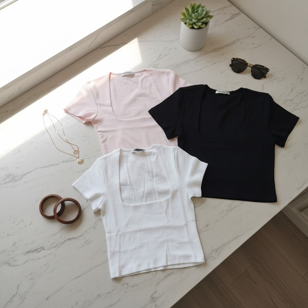 Three short sleeve square neck tops in pale pink, black and white laid flat