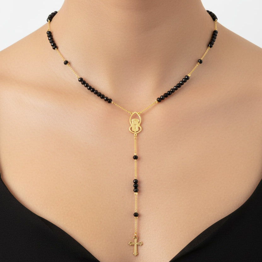 Black beaded St Charbel necklace with gold accents worn by a woman
