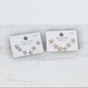 Pair of star stud earring sets on display cards with branding on a marble surface