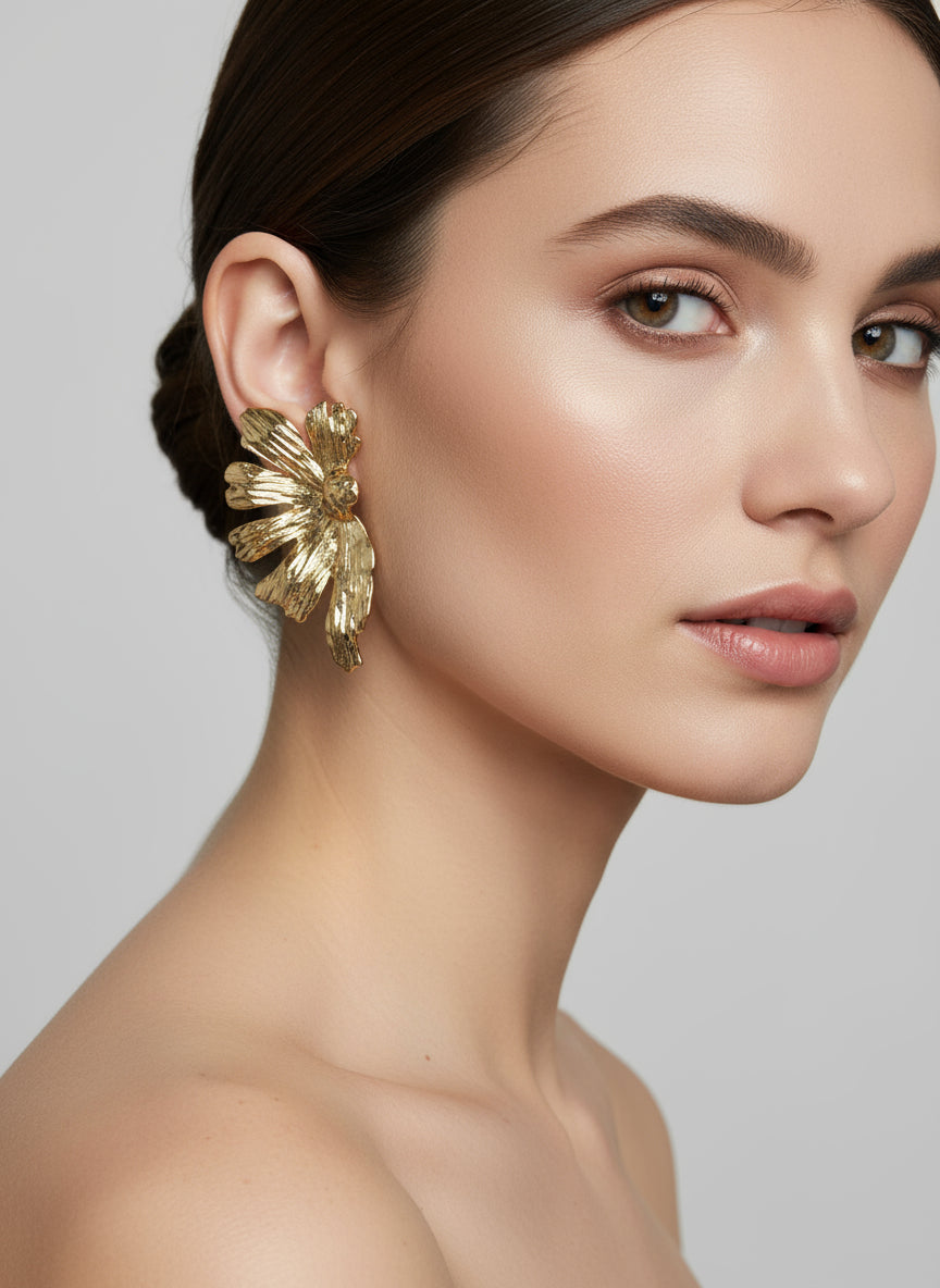Woman wearing starfire gold earrings against a neutral background