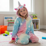 Pastel rainbow unicorn onesie worn kneeling on a rug