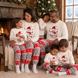 Parents and four kids in matching snowman fleece pyjamas relaxing together in a cosy cabin