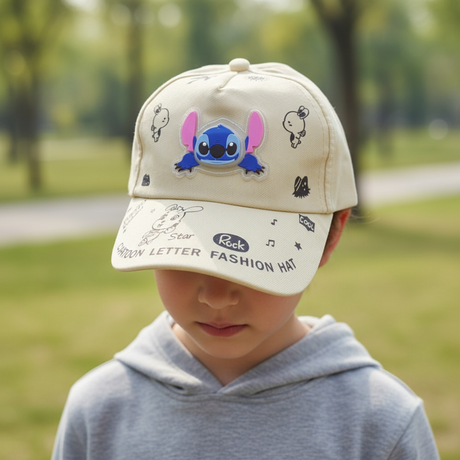 Boy in a park wearing a cream cap with a blue cartoon alien patch and doodle print peak