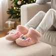 Person wearing pink stitch Pantoufle with cartoon face design on a couch in a cozy living room.