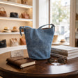 Blue stitched bucket crossbody bag with whipstitch seam detail