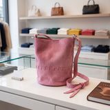 Pink stitched bucket crossbody bag with an adjustable shoulder strap