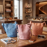 Blue, pink and coral stitched bucket crossbody bags on a store counter