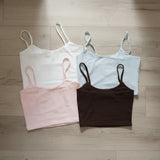 Four strappy ribbed crop camis in white, light blue, pale pink and brown laid flat