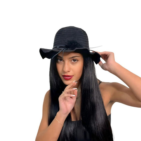 Black wavy brim hat with a bow band worn with a finger to the lips