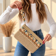 Beige jute clutch with a straw panel, pom poms and blue star beads on a pom pom strap
