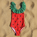 Strawberry-themed swimsuit with green top and red body with black seeds on a white background
