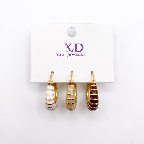 Three single striped enamel huggie earrings in white, beige and brown on a card
