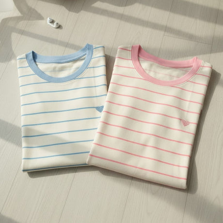 Blue and pink striped tees folded on a pale wooden surface