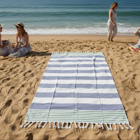 Striped beach towel on sand with people in the background