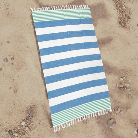 Striped beach towel with blue, green, and white stripes on a sandy background