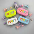 Four colorful 'STUFF' pouches in yellow, pink, blue, and white with accessories on a grey background