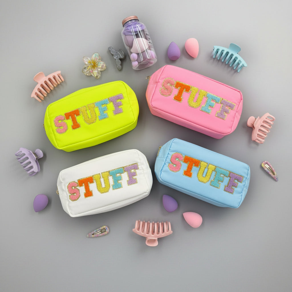 Four colorful 'STUFF' pouches in yellow, pink, blue, and white with accessories on a grey background