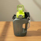 Grey water bottle with a light green cap and black strap on a light grey background