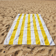 Yellow and white striped beach towel on sand with 75x140 cm size
