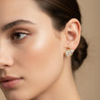 Close-up of a woman wearing a swan-shaped earring against a neutral background