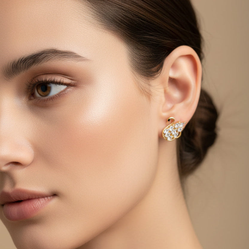Close-up of a woman wearing a swan-shaped earring against a neutral background