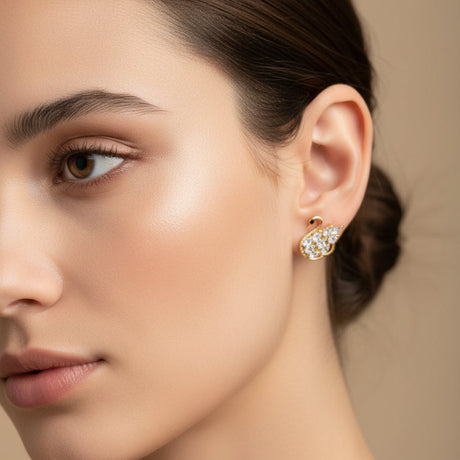 Close-up of a woman wearing a swan-shaped earring against a neutral background