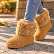 Woman in jeans walking in tan faux suede platform boots with a fluffy fur cuff
