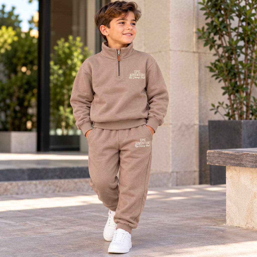 Boy walking in a taupe brown half zip sweatshirt and jogger set with Epic Adventure print and white sneakers