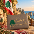 Handmade taupe grey pouch with gold Arabic I love you Lebanon embroidery and a green cedar, with the Lebanese flag behind