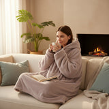 Taupe hooded blanket worn curled up on a sofa with a book and a warm drink