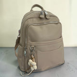 Taupe grained backpack with twin front zips and a woven daisy charm