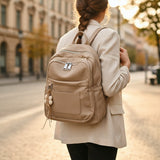 Woman wearing taupe pebbled leather backpack with flower charm, Jack Gifts Online Lebanon