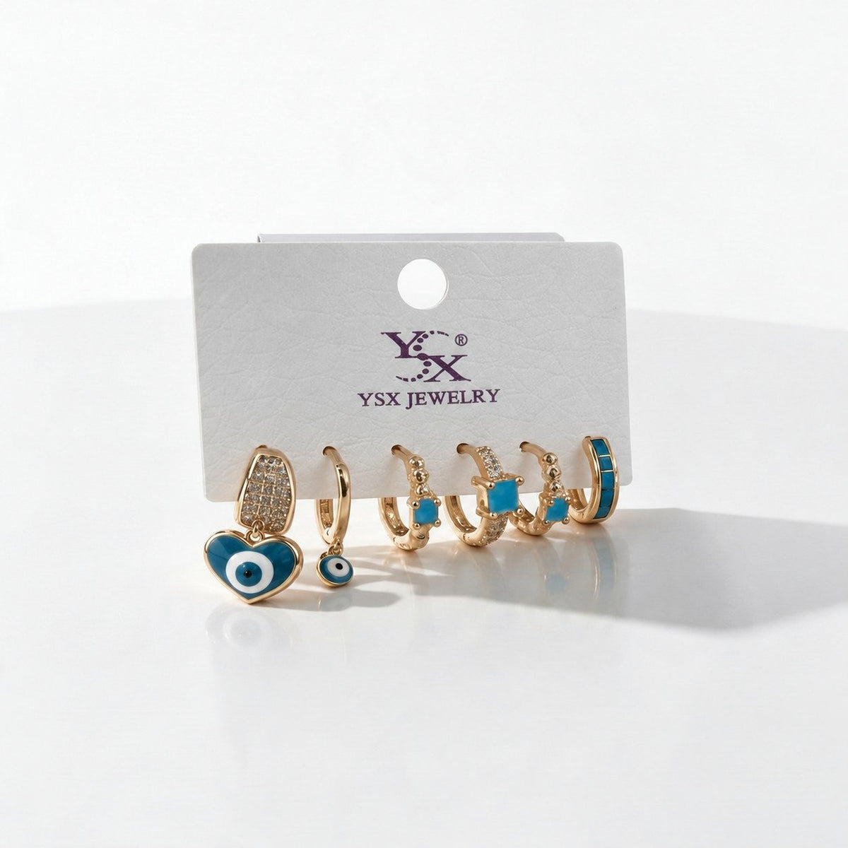 Six single huggie earrings in gold and teal with a heart evil eye drop and turquoise stones