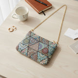 Mandala triangle tapestry bag laid on a desk beside a mug