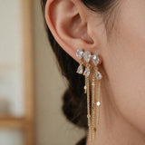 Gold chain tassel earring with clear pear cut crystals hanging from the earlobe