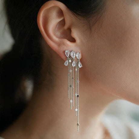 Silver teardrop crystal cluster earring with long sequin chain tassels worn on the ear