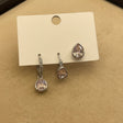 Set of teardrop crystal earrings on a display card on a beige surface