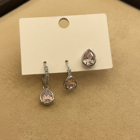 Set of teardrop crystal earrings on a display card on a beige surface