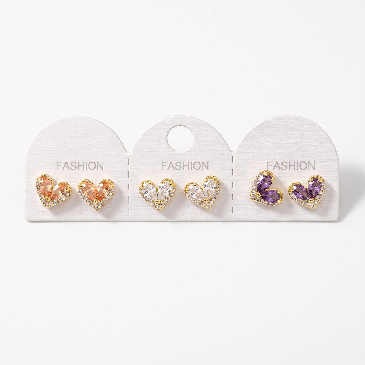 Three pairs of teardrop crystal heart stud earrings in peach, clear and purple