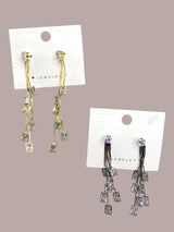 Two pairs of gold and silver teardrop earrings on a jewelry display card against a beige background
