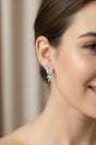 Close-up of a woman wearing a pair of teddy earrings with a neutral background
