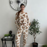 Teddy bear print fleece pyjama set worn standing beside a clock