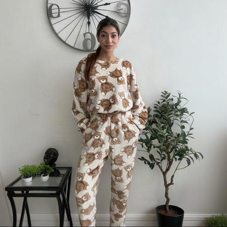 Teddy bear print fleece pyjama set worn standing beside a clock