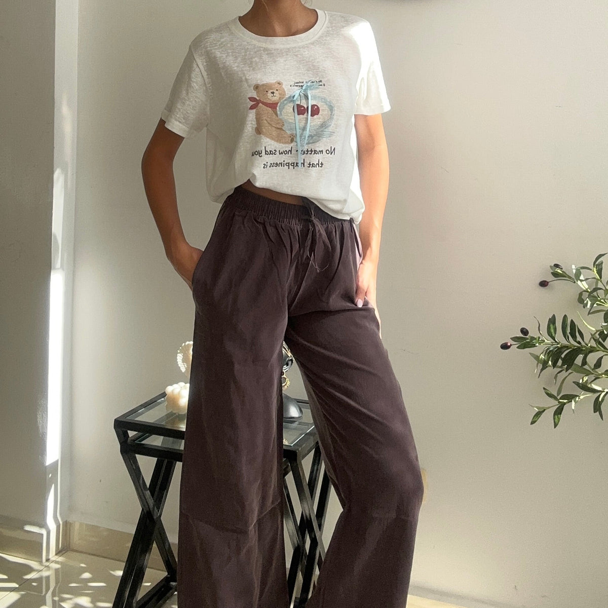 Teddy bear print crop tee worn with brown trousers and hands in pockets