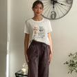 White crop tee with a teddy bear print worn with dark brown wide leg trousers