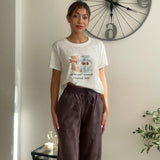 White crop tee with a teddy bear print worn with dark brown wide leg trousers