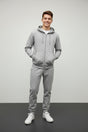 Teenage boy in a grey zip up hooded jacket and matching grey joggers with white sneakers